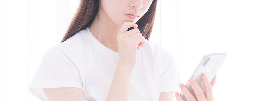 スマホ画面を見て悩む女性